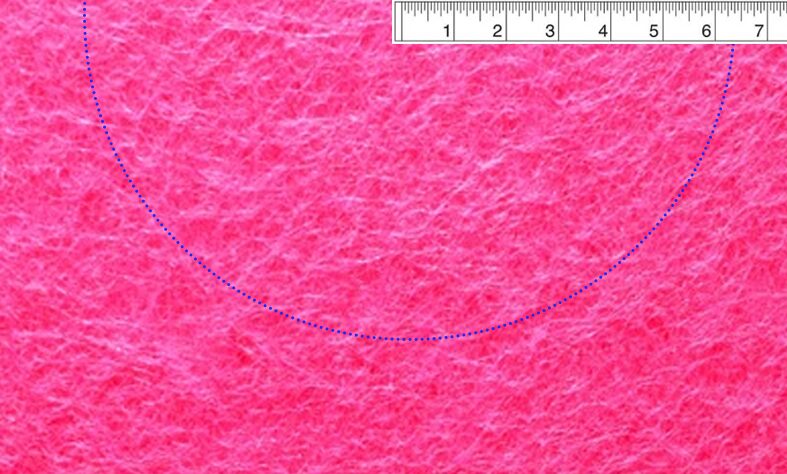 folded layer of pink felt, with a measuring tape set on top and a pen marking the fabric at 6.4 inches to create a half circle