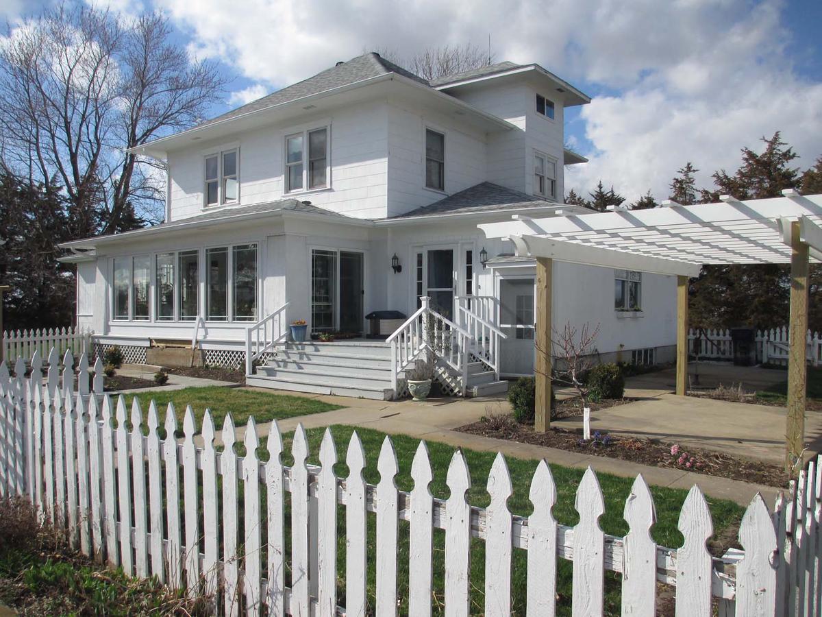 A sunny 1950s suburban neighborhood with white picket fences and colorful houses