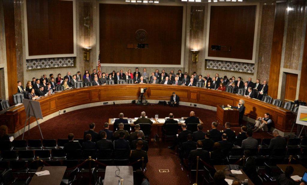 A Congressional hearing room with legislators discussing commemorative coin legislation