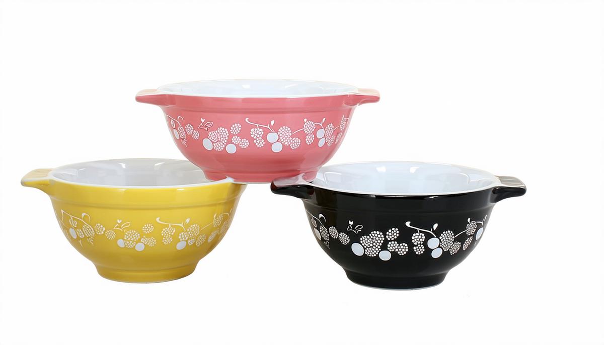 Three Pyrex bowls displaying the Gooseberry pattern in different color combinations: pink on white, white on pink, and black on yellow